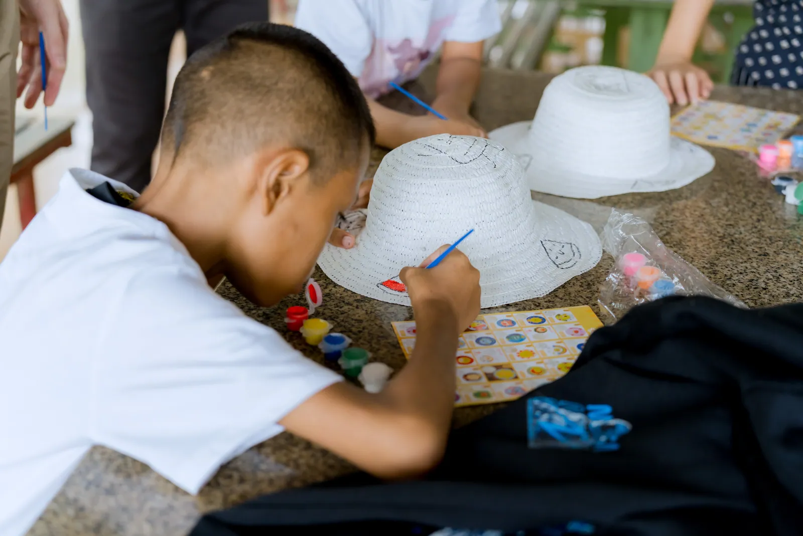 A child painting a white hat
